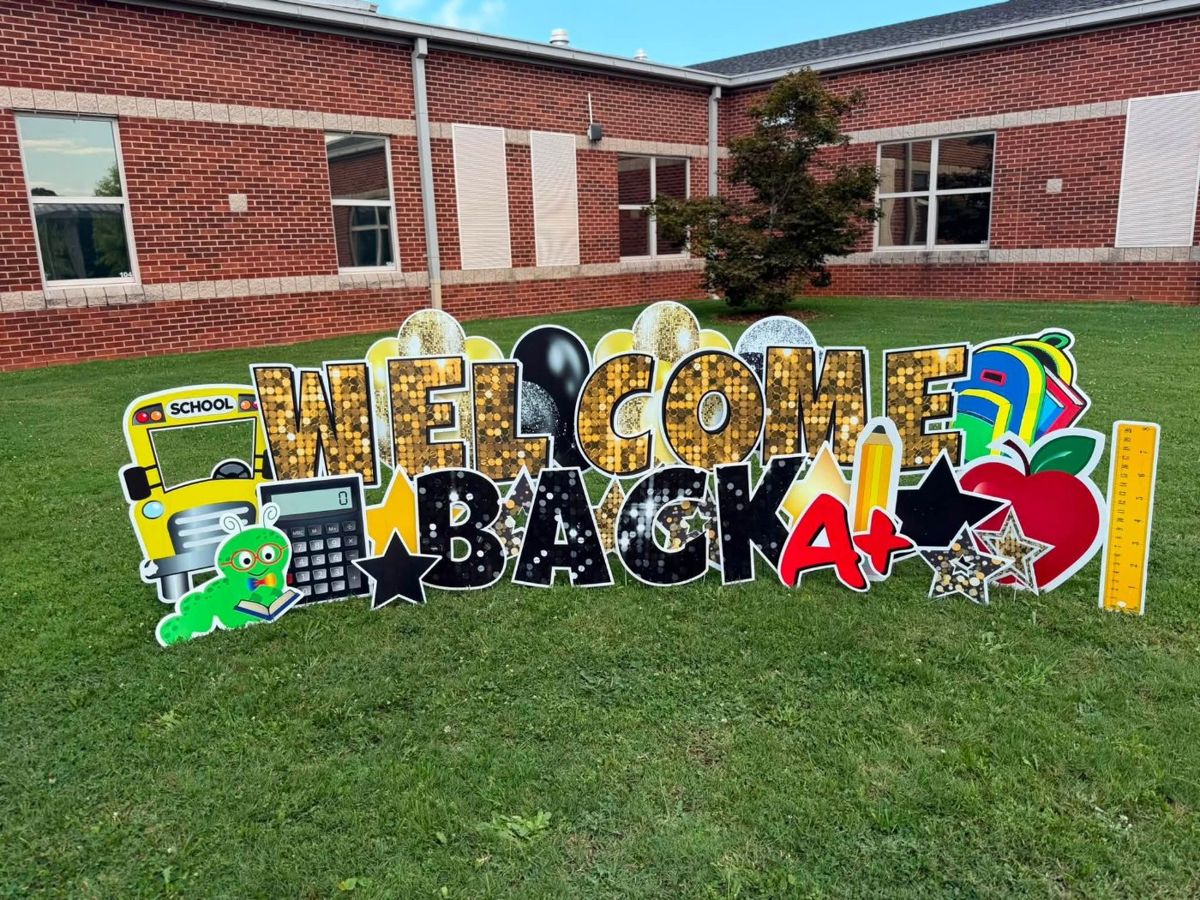 Gold and black Welcome Back display with a school bus and apple in front of a school